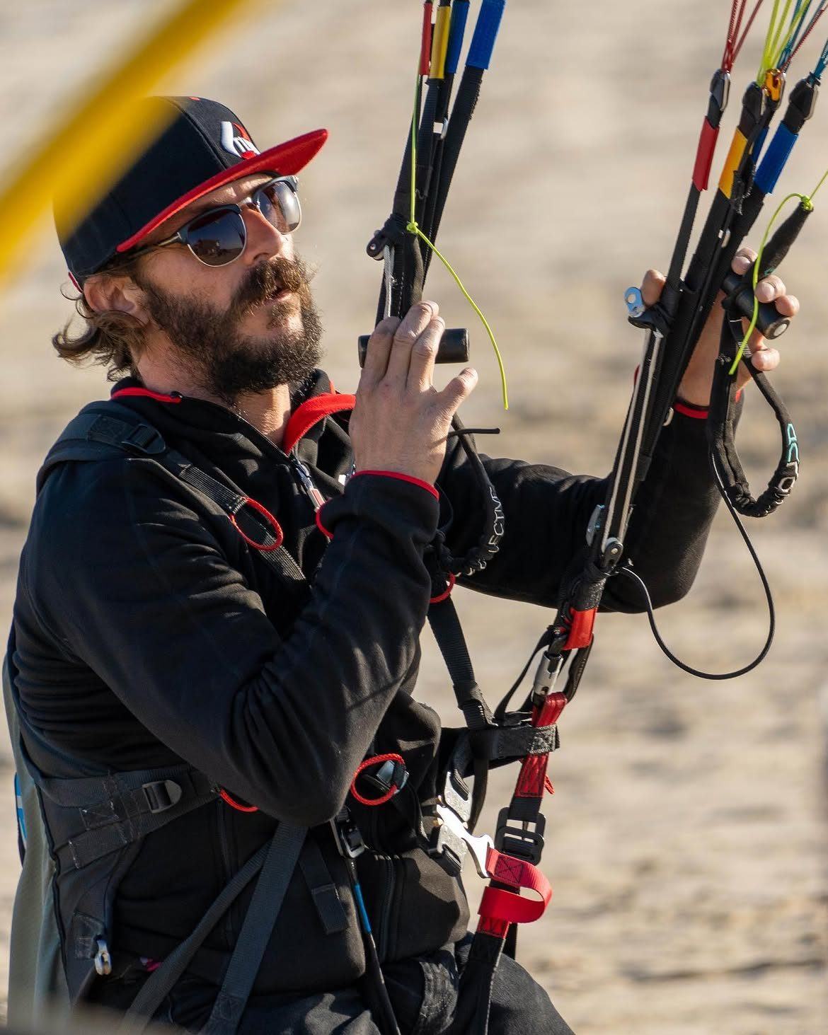 Javi Tejeiro holding both risers of a paraglider, looking up at the wing