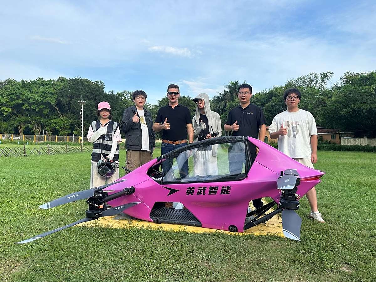 A pink S-ZERO on a grass field with its owners standing around it